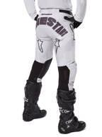 Alpinestars 2025 Racer Hollow Pants, pantalon de motocross, brun camouflage clair, vue arrière du pilote montrant un logo imposant sur l'assise et des empiècements extensibles noirs sur le bas des jambes, associé à des bottes Tech 7 noires