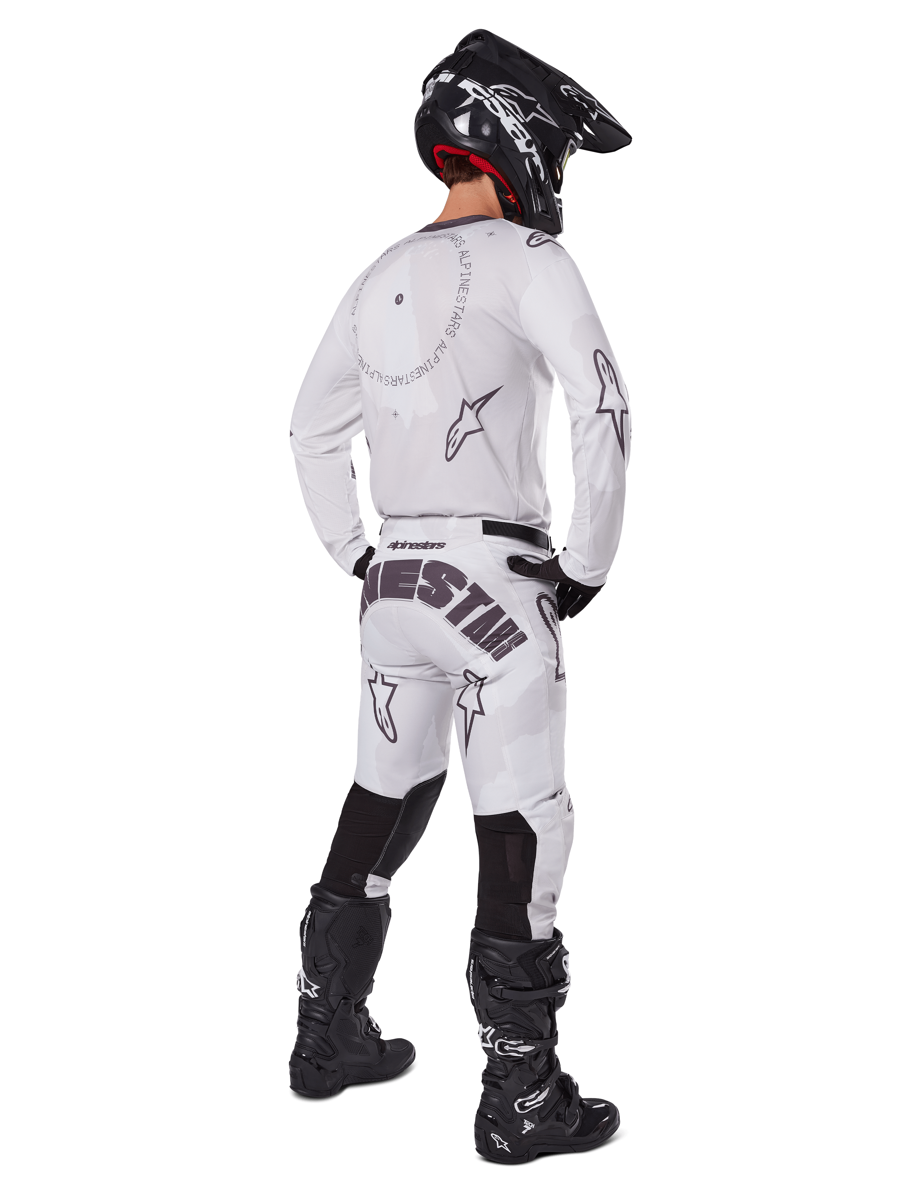 Alpinestars 2025 Racer Hollow Pants, pantalon de motocross, brun camouflage clair et blanc, vue arrière montrant un marquage noir imposant sur l'assise et des logos étoiles, porté avec un maillot assorti, des bottes noires et un casque noir pour un look de course tout-terrain complet
