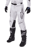 Alpinestars 2025 Racer Hollow Pants, pantalon de motocross, camouflage blanc et gris, avec de grands logos étoiles aux contours noirs et des empiècements en cuir noir à l'intérieur des genoux, porté avec des bottes et des gants de motocross noirs, conception durable pour la course tout-terrain.