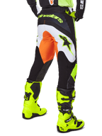 Alpinestars 2025 Fluid Wurx Pants, pantalon de motocross, jaune et noir avec des accents orange et blancs, vue de dos porté avec des bottes jaune vif assorties, construction durable avec logos audacieux pour la conduite tout-terrain
