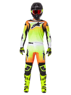 Pantalon Alpinestars Fluid Wurx 2025, pantalon de motocross, jaune et noir avec dégradé orange et blanc, porté avec maillot assorti, bottes jaune vif et casque noir avec lunettes rouges, tenue de motocross complète