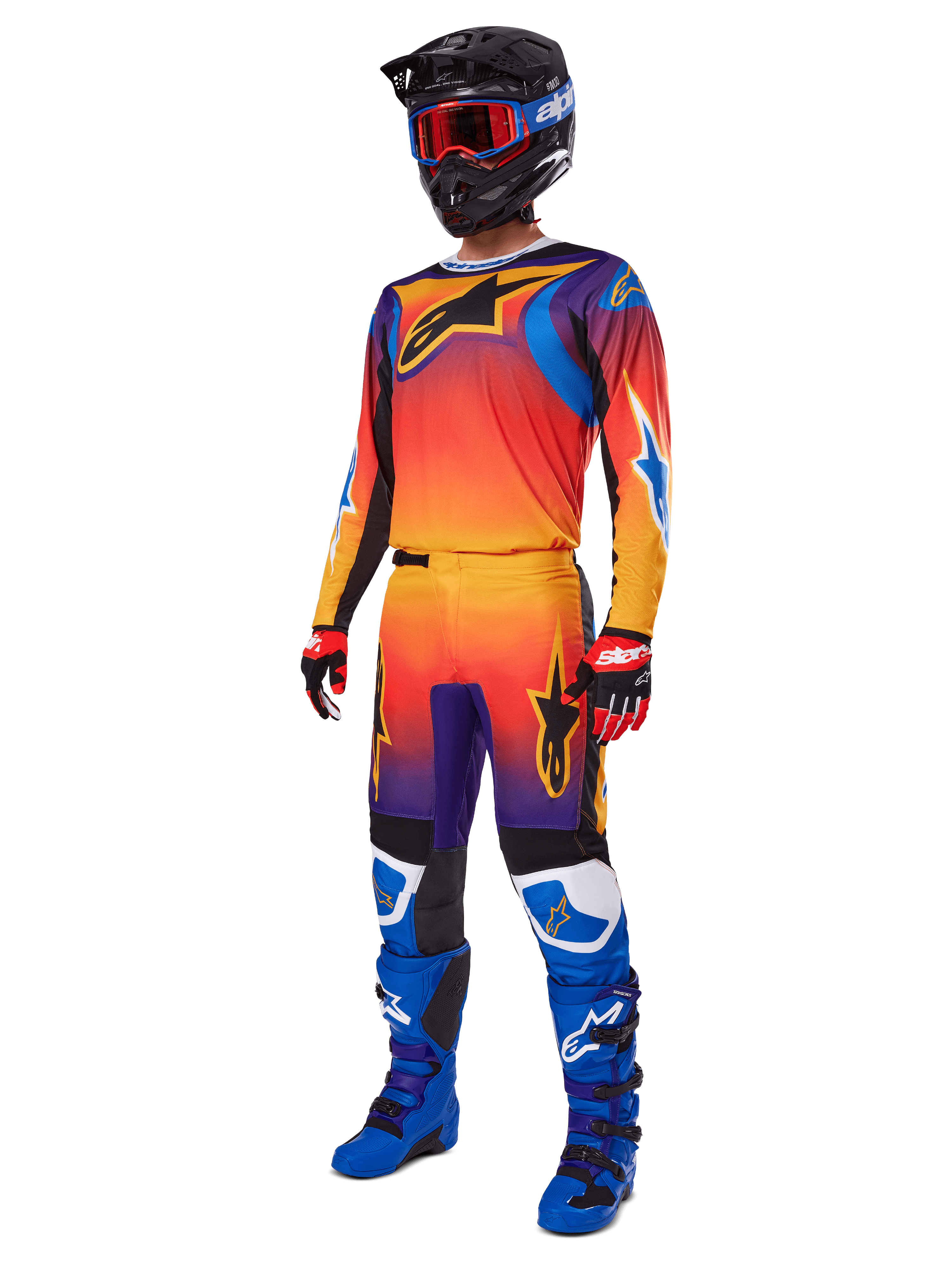 Motocross rider wearing complete racing gear, Alpinestars 2025 Fluid Wurx Pants and matching jersey in a multicolor orange, red, and purple gradient, black helmet with red goggles, blue and black boots, red and black gloves, coordinated outfit for off-road racing