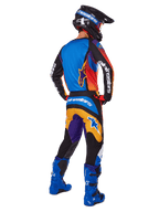 Motocross rider from the back wearing Alpinestars 2025 Fluid Wurx Pants, Multicolor design with blue, orange, yellow, and purple accents, paired with a matching jersey, bright blue boots, and black helmet, complete off-road racing gear.