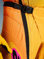 Alpinestars 2026 Techstar Nomur Pants, pantalon de motocross, orange, jaune et rose, gros plan sur la zone de la taille présentant la fermeture par boucle magnétique SX2, sangle de réglage noire et perforations de ventilation découpées au laser sur un matériau ripstop durable