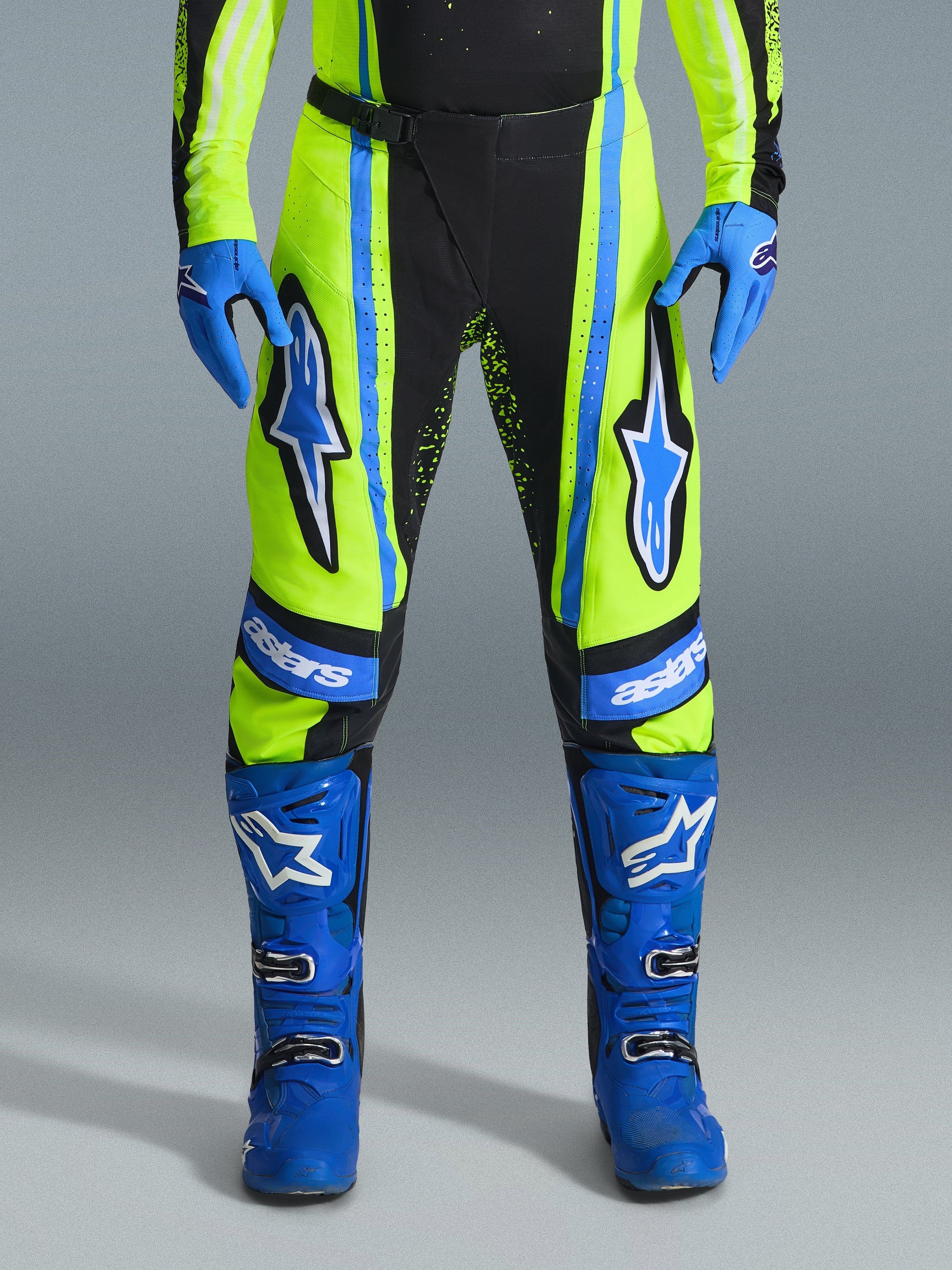 Alpinestars Techstar Nomur Pants 2026, pantalon de motocross, jaune fluo et bleu marine avec accents bleus, porté avec des gants et des bottes bleus assortis, avec des logos Astars sur les cuisses et une conception haute performance pour la course tout-terrain