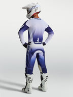 Alpinestars Racer Air Amber, pantalon de motocross pour homme, bleu et blanc, construction perforée à haut flux d'air, vue de dos sur un pilote avec bottes et casque blancs