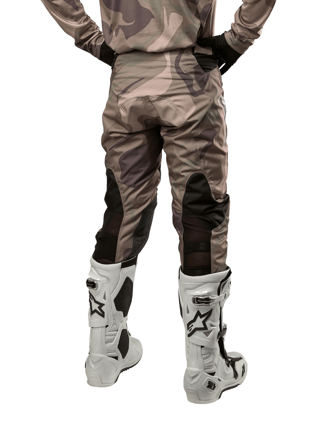 Alpinestars 2024 Racer Tactical Pants, pantalon de motocross, camouflage vert militaire et marron, vue arrière montrant le motif camouflage et les panneaux extensibles noirs respirants sur le bas des jambes, porté avec des bottes de motocross blanches, équipement technique durable pour la conduite tout-terrain