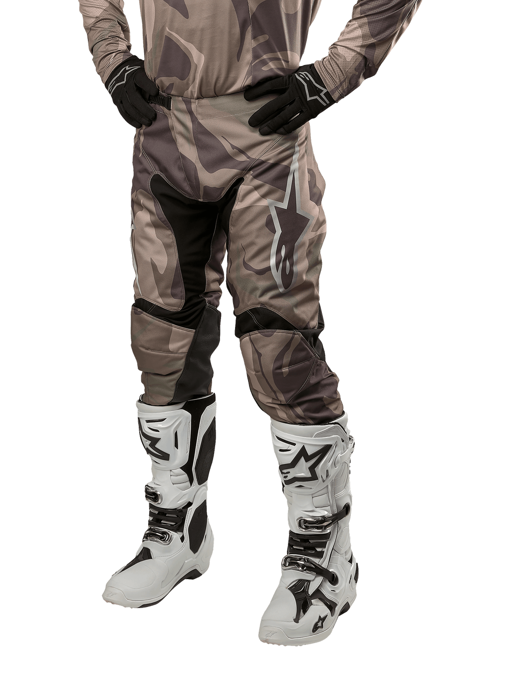 Alpinestars 2024 Racer Tactical Pants, pantalon de motocross, camouflage vert militaire et marron, porté avec un maillot camouflage assorti, des gants noirs et des bottes blanches avec des logos étoiles, doté de panneaux extensibles noirs et d'un design ergonomique, tenue tout-terrain sur fond blanc