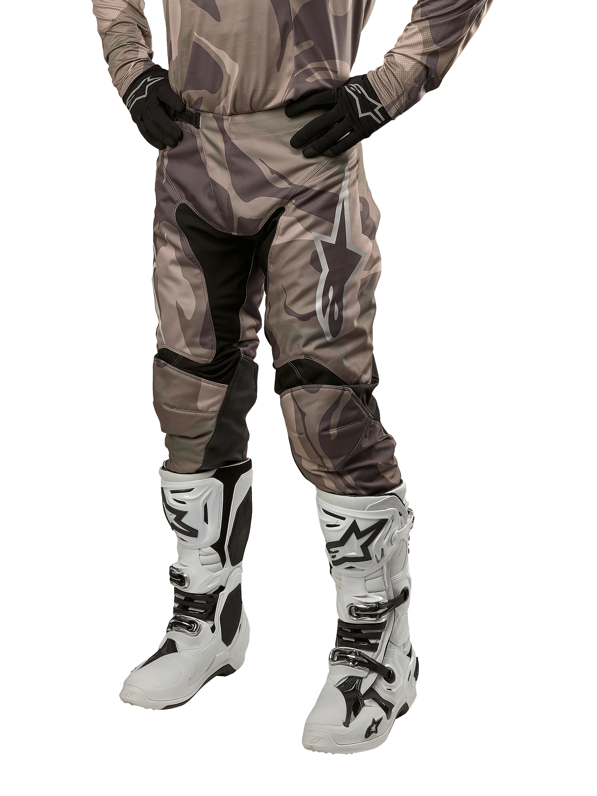 Alpinestars 2024 Racer Tactical Pants, pantalon de motocross, camouflage vert militaire et marron, porté avec un maillot camouflage assorti, des gants noirs et des bottes blanches avec des logos étoiles, doté de panneaux extensibles noirs et d'un design ergonomique, tenue tout-terrain sur fond blanc