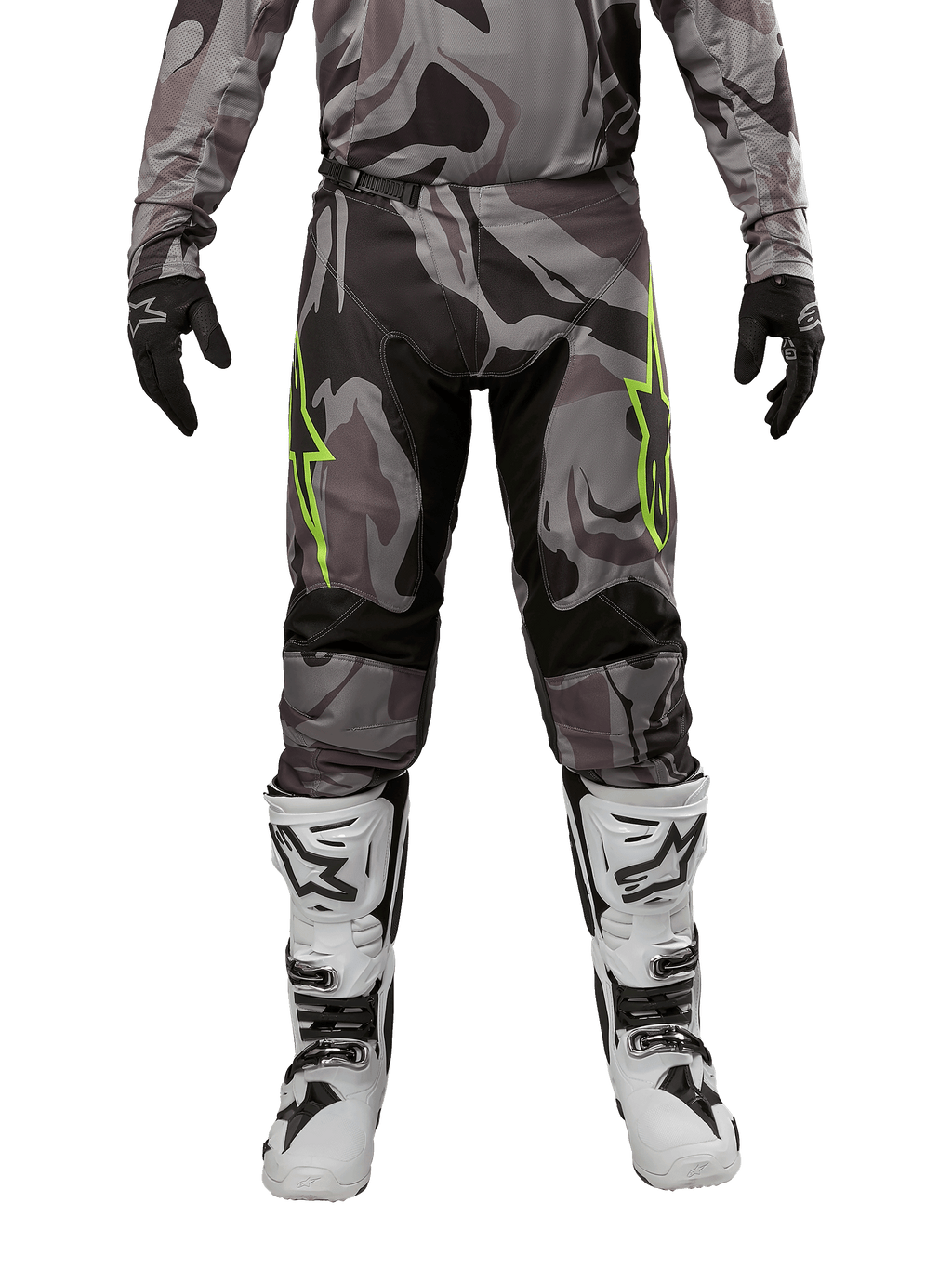 Pantalon Alpinestars Racer Tactical 2024, pantalon de motocross, Cast Gray Camo Magnet, porté avec un maillot camouflage assorti, des gants noirs et des bottes blanches et noires, avec des logos étoilés vert citron sur les cuisses et des empiècements stretch noirs, vue de face d'un équipement de pilotage tout-terrain.