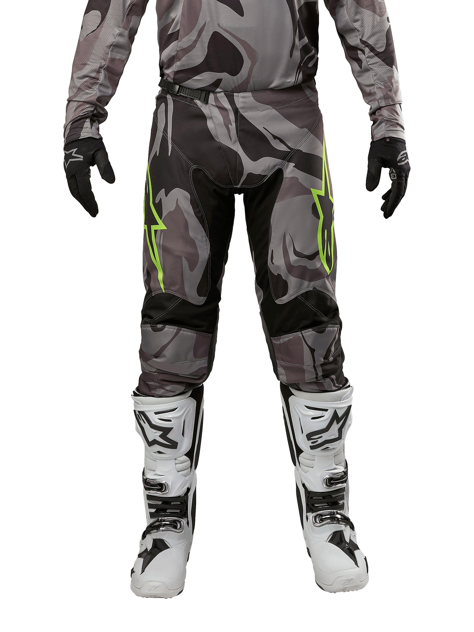 Pantalon Alpinestars Racer Tactical 2024, pantalon de motocross, Cast Gray Camo Magnet, porté avec un maillot camouflage assorti, des gants noirs et des bottes blanches et noires, avec des logos étoilés vert citron sur les cuisses et des empiècements stretch noirs, vue de face d'un équipement de pilotage tout-terrain.
