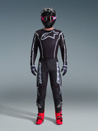 Ensemble Alpinestars 2026 Fluid Apex, tenue de motocross, noir avec accents gris, maillot arborant un grand logo Astars blanc, pantalon assorti avec un marquage imposant, casque noir avec lunettes roses et bottes rouge vif, kit complet de course tout-terrain