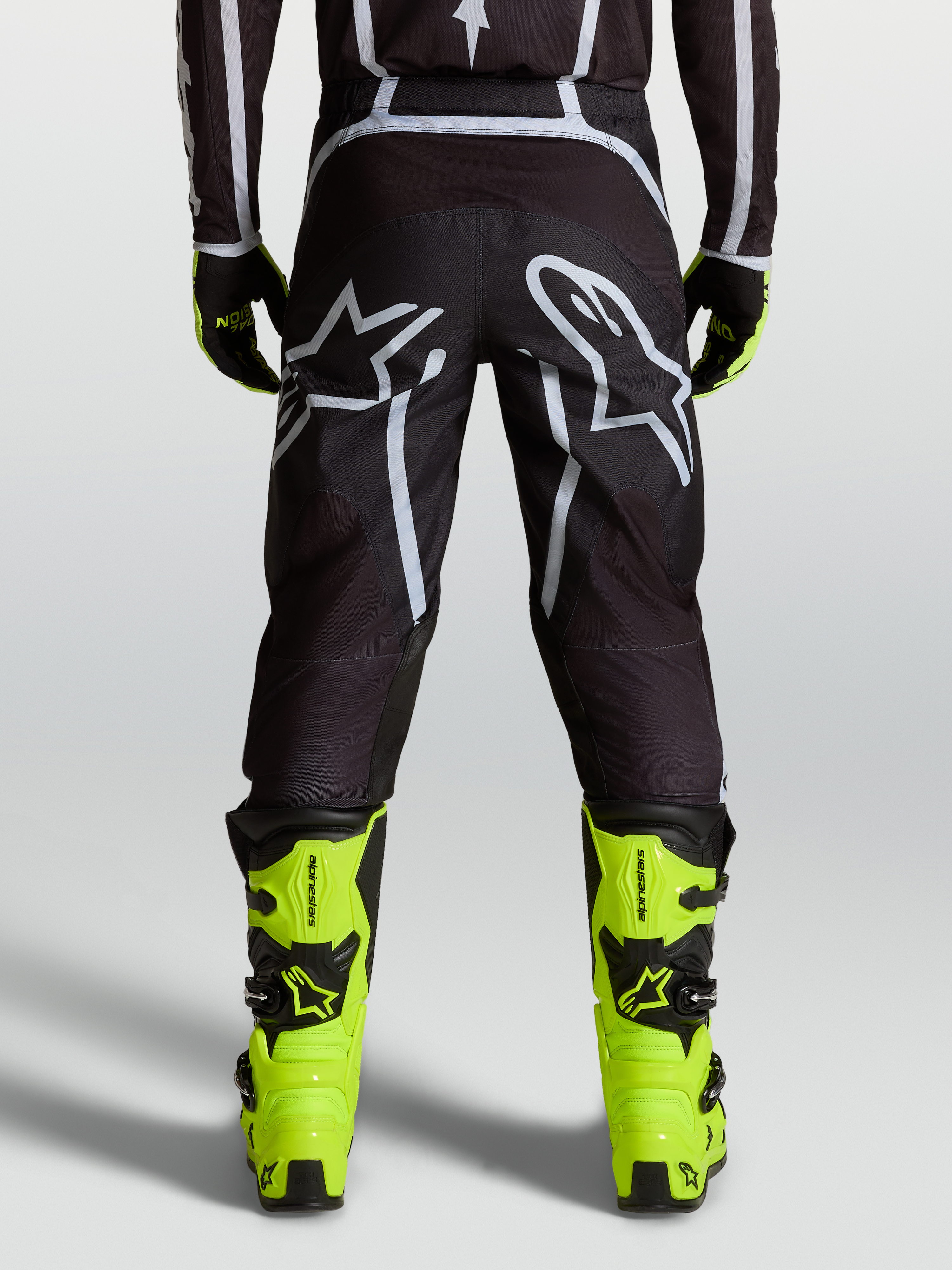 Alpinestars Fluid Apex V2 Pants, motocross riding pants in Black and Silver, featuring a pre-curved ergonomic fit and reinforced high-wear zones for off-road performance.
