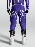 Alpinestars Pantalon Fluid Apex V2, pantalon de motocross tout-terrain, bleu et blanc, vue de dos sur mannequin avec bottes blanches, poly-tissu 600D durable et design ergonomique.