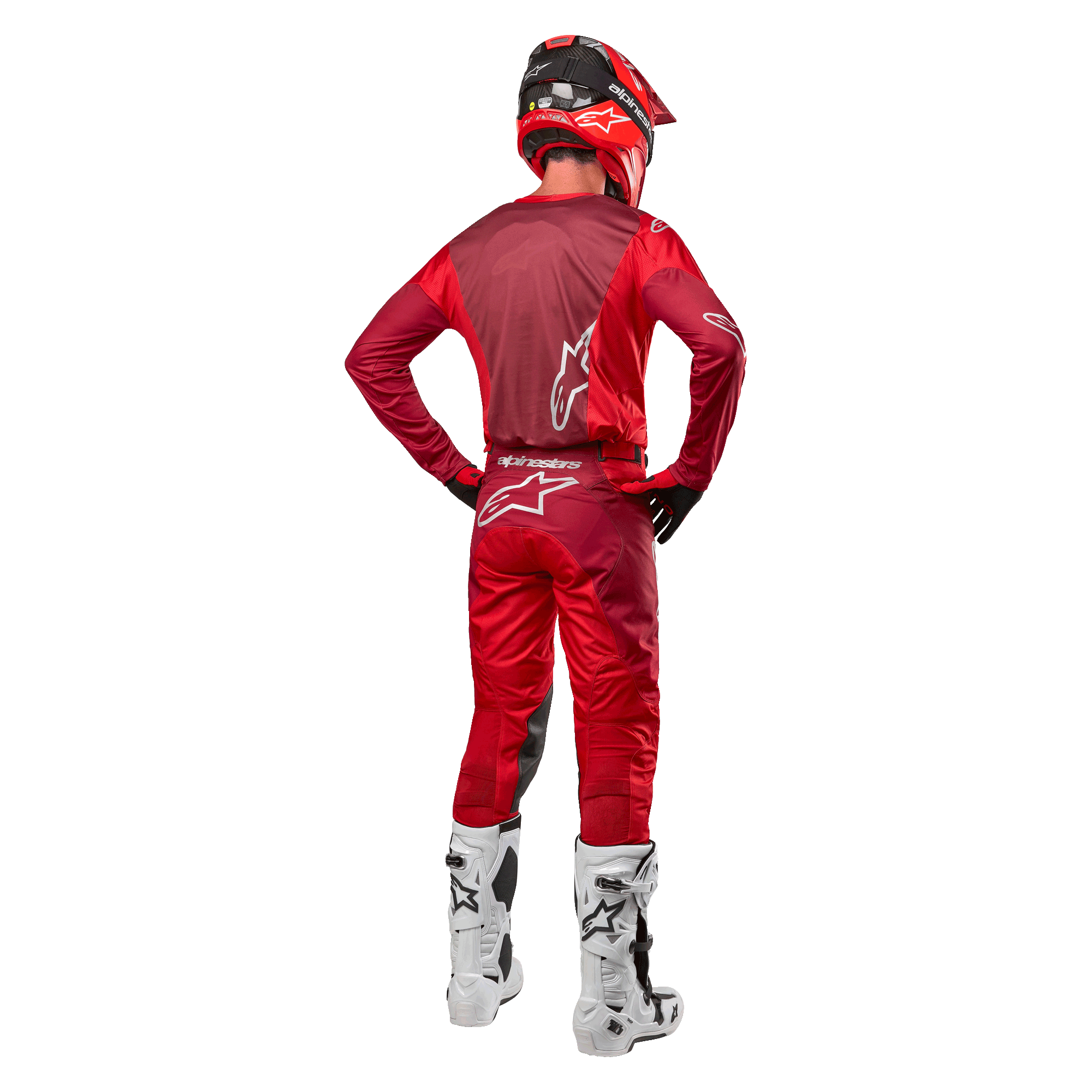 Pantalon et maillot assorti Alpinestars Racer Hoen 2024 en Mars Red Burgundy, vue arrière d'un pilote de motocross en tenue complète avec casque rouge et bottes blanches, illustrant la coupe athlétique et le marquage pour la course tout-terrain.