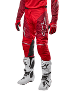 Alpinestars Racer Hoen Pants 2024, pantalon de motocross, rouge Mars et bordeaux, porté avec un maillot et des gants rouges assortis et des bottes blanches, doté de panneaux de genoux en cuir noir et de logos blancs, équipement technique durable pour la course tout-terrain
