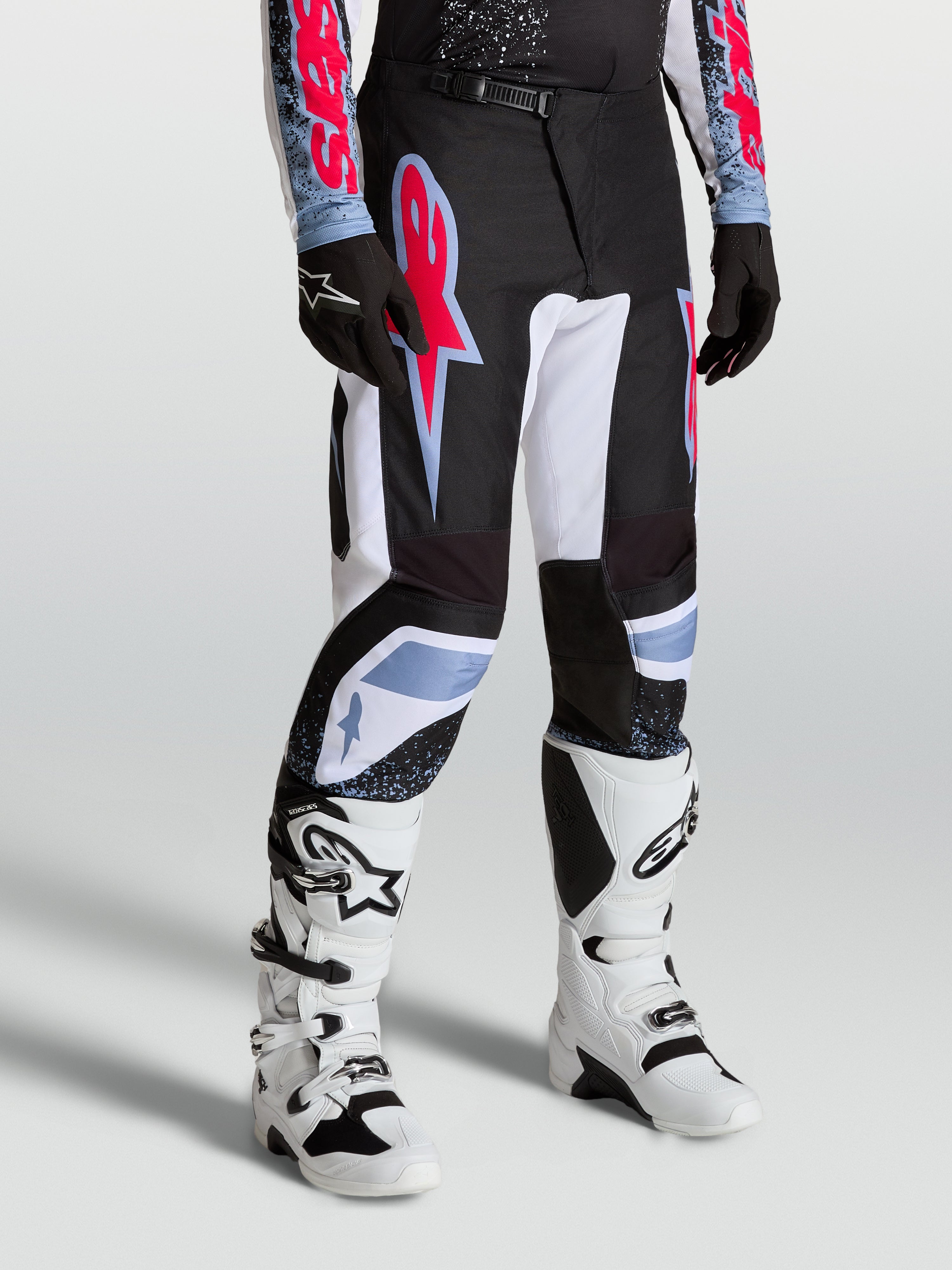 Pantalon Fluid Drag Alpinestars, pantalon motocross homme, noir et blanc avec accents rouge fluo et bleu clair.
