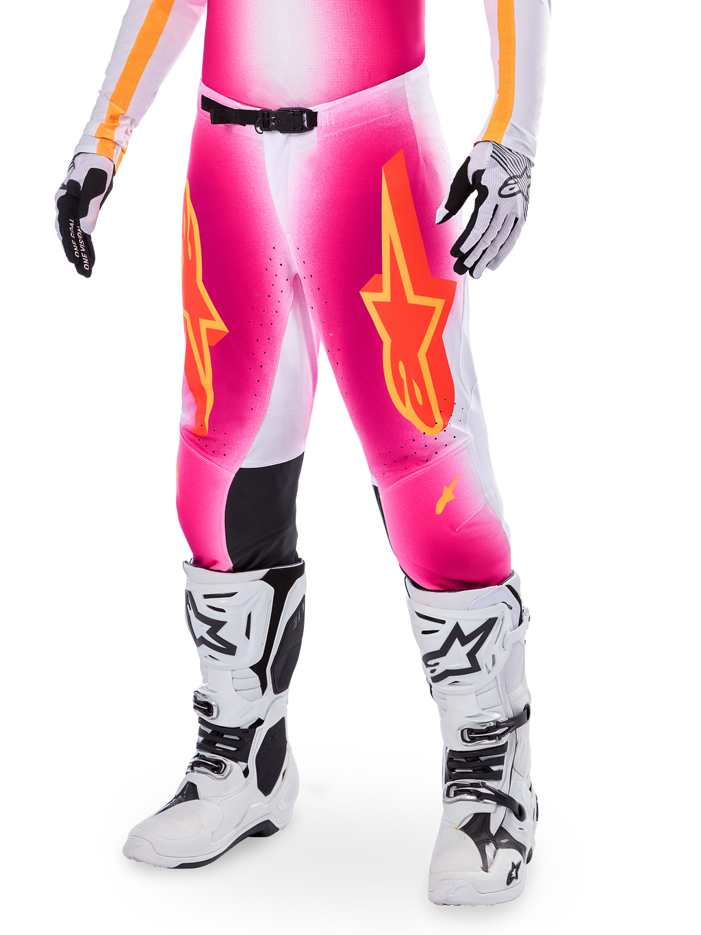 Alpinestars Supertech AFD MIG Limited Edition, pantalon de motocross, rose avec des logos d'étoiles orange et jaunes, porté avec des bottes de motocross blanches et des gants noirs et blancs, doté de panneaux intérieurs noirs aux genoux et d'une coupe athlétique, élément d'un ensemble d'équipement de course haute performance