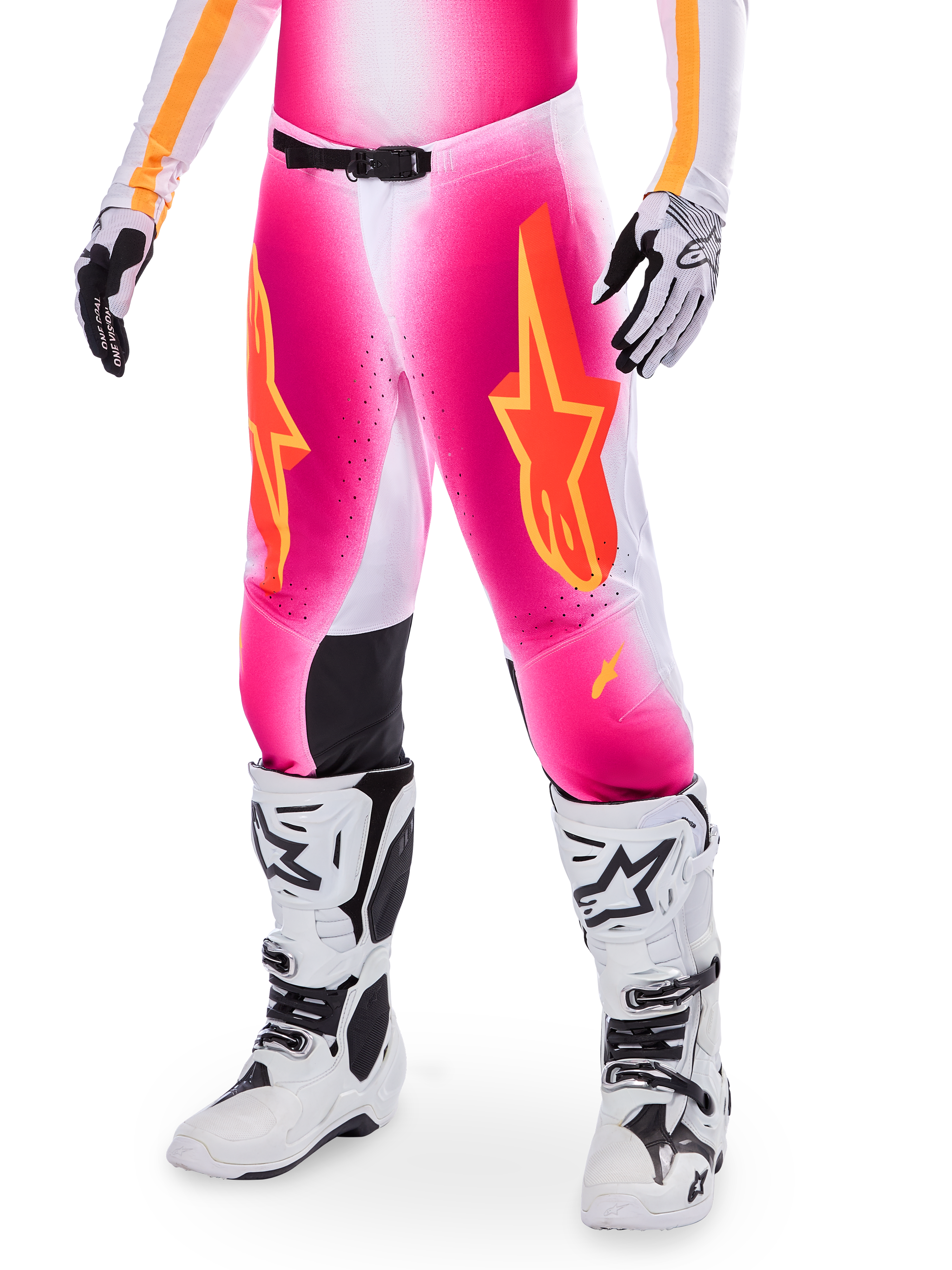 Alpinestars Supertech AFD MIG Limited Edition, pantalon de motocross, rose avec des logos d'étoiles orange et jaunes, porté avec des bottes de motocross blanches et des gants noirs et blancs, doté de panneaux intérieurs noirs aux genoux et d'une coupe athlétique, élément d'un ensemble d'équipement de course haute performance