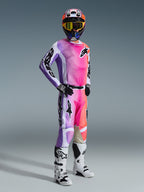 Pilote de motocross portant le maillot Alpinestars Racer Air Portl 2026 et son pantalon assorti, dégradé multicolore vif rose, violet et orange avec accents blancs, casque coloré coordonné et masque jaune, bottes blanches et noires, tenue de course complète pour la performance tout-terrain