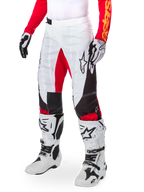 Alpinestars Techstar Deep Édition Limitée, pantalon de motocross, blanc, noir et rouge vif, porté avec des bottes et des gants blancs et noirs, doté de panneaux avant blancs avec des accents rouges et de détails latéraux noirs, conçu pour la course tout-terrain haute performance