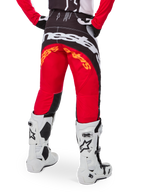 Alpinestars Techstar Deep Édition Limitée, pantalon de motocross, noir, blanc et rouge vif, vue arrière avec logo Alpinestars blanc imposant sur l'assise et marquage orange, porté avec des bottes techniques blanches pour la compétition tout-terrain professionnelle