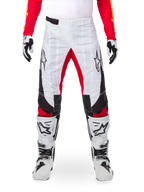 Alpinestars Limited Edition Techstar Deep Pants, pantalon de motocross, noir, blanc et rouge vif, porté avec un maillot rouge assorti, des gants et des bottes blancs et noirs, comprenant des panneaux avant blancs, des accents rouges à l'intérieur des jambes, des panneaux latéraux noirs, des logos Alpinestars sur les cuisses et des détails perforés au laser pour la ventilation.