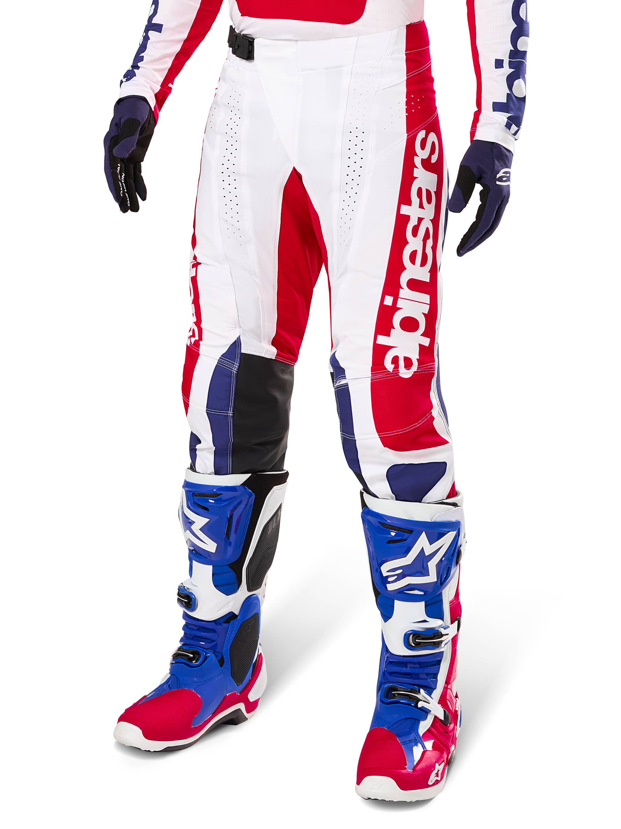 Alpinestars Limited Edition Techstar Fortitude Pants, pantalon de motocross, rouge vif, blanc et bleu, porté avec des bottes et gants tout-terrain assortis, logo vertical sur la jambe, panneaux perforés respirants et sections renforcées noires aux genoux, coupe de course athlétique