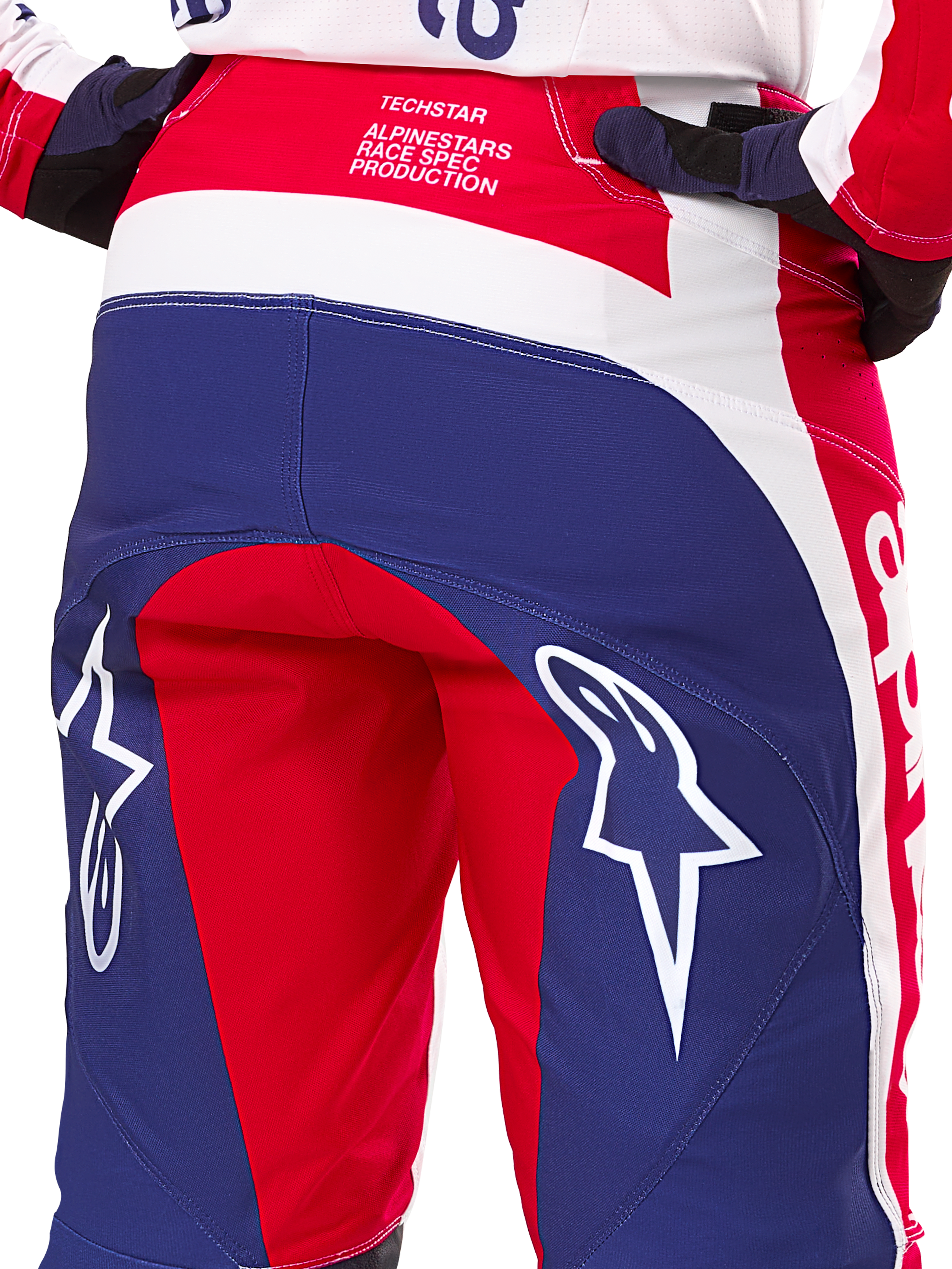 Alpinestars Pantalon Techstar Fortitude Édition Limitée, pantalon de motocross, rouge, blanc et bleu, vue arrière avec grands logos d'étoile blancs sur l'assise et marquage Techstar Race Spec, textile haute performance durable pour le tout-terrain