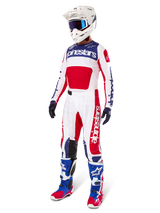 Alpinestars Pantalon Techstar Fortitude Édition Limitée, tenue de motocross, rouge, blanc et bleu, porté avec maillot assorti, casque blanc, lunettes bleues et bottes bleues et rouges, équipement de course professionnel pour compétition tout-terrain