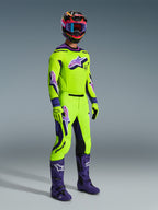 Ensemble d'équipement Alpinestars Supertech Vista 2026, pilote de motocross professionnel portant un maillot et un pantalon vert citron éclatant avec des accents et des logos violets, gants vert citron assortis, bottes violettes et casque multicolore avec lunettes bleues, tenue de course tout-terrain coordonnée