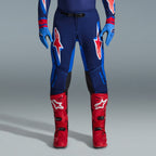 Ensemble d'équipement Alpinestars Supertech Vista 2026, pantalon de motocross bleu marine et bleu vif avec logos rouges et blancs, associé à des gants bleu clair et des bottes de motocross rouge vif, tenue de course professionnelle.