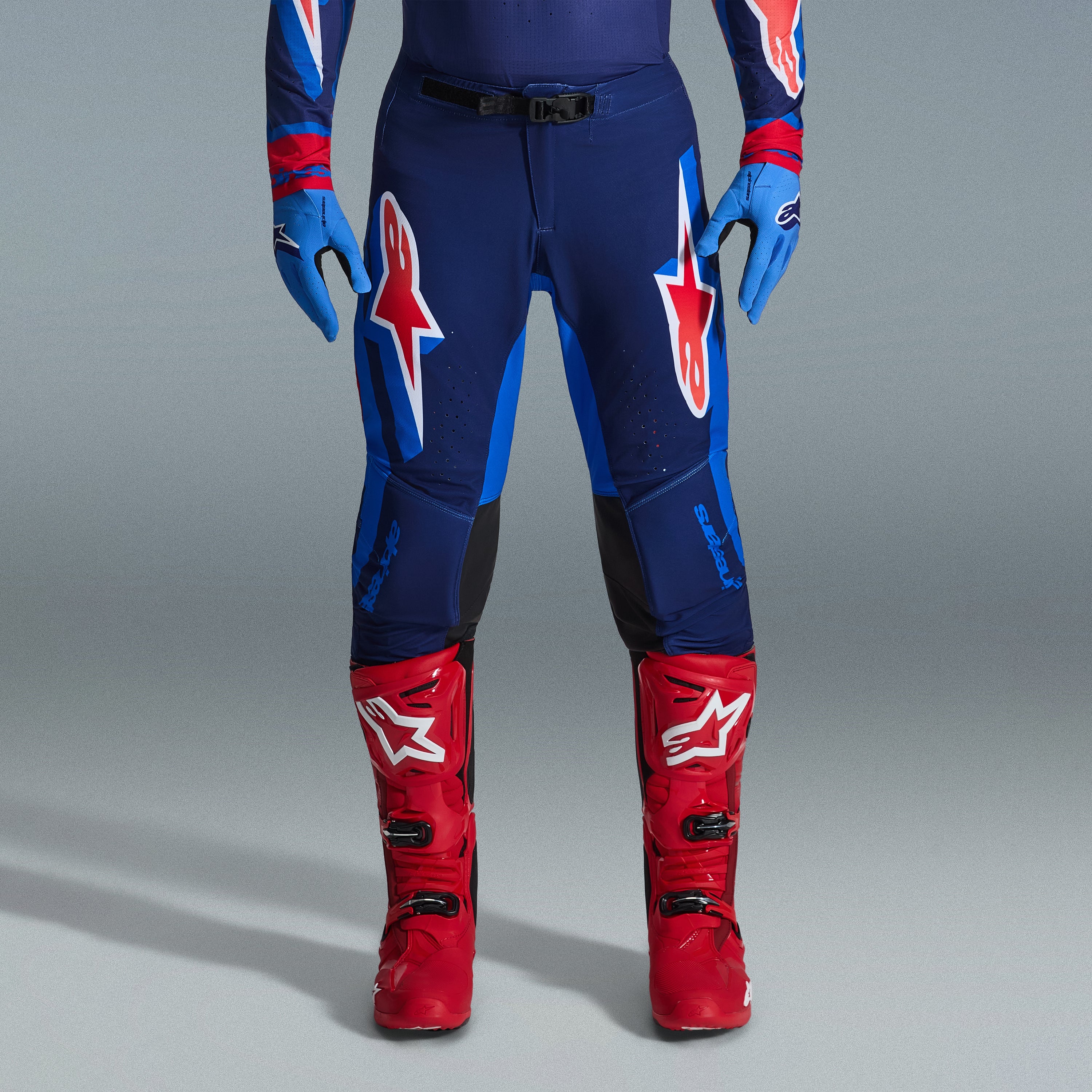 Ensemble d'équipement Alpinestars Supertech Vista 2026, pantalon de motocross bleu marine et bleu vif avec logos rouges et blancs, associé à des gants bleu clair et des bottes de motocross rouge vif, tenue de course professionnelle.