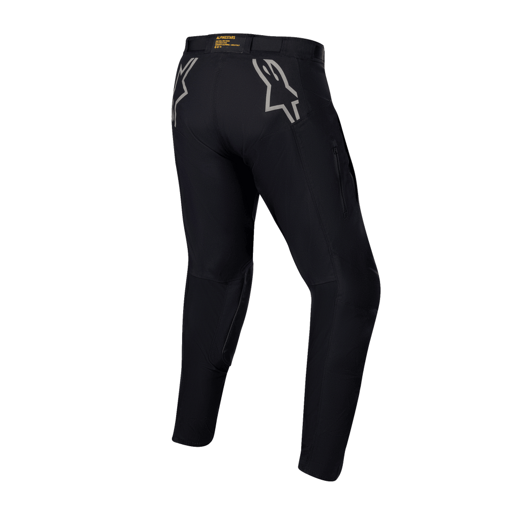 Pantalon Alpinestars Techdura, pantalon d'enduro et tout-terrain noir, vue arrière avec logos étoiles gris sur les hanches, marquage jaune sur la ceinture arrière, matériau en polyamide extensible robuste avec une conception durable pour la pratique de la moto