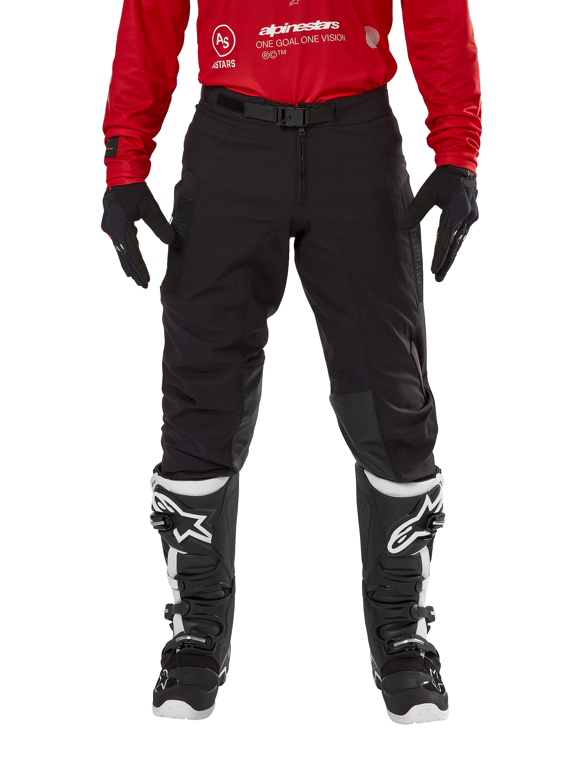 Pantalon Alpinestars Techdura, pantalon d'enduro et de tout-terrain, noir, porté avec un maillot Alpinestars rouge et des bottes noires et blanches, doté d'une construction en toile extensible robuste, d'une boucle de ceinture magnétique réglable et de renforts de genoux en cuir pour la performance tout-terrain
