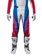 Alpinestars Techstar Pneuma Pants 2024, pantalon de motocross, bleu Mars, rouge et blanc, présentant un design angulaire multicolore avec des accents violets, associé à des bottes de motocross blanches et noires et des gants assortis, coupe de course athlétique pour la performance tout-terrain