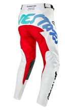 Alpinestars Racer Hana Pants 2024, pantalon de motocross, blanc multicolore, vue latérale arrière présentant un empiècement fessier rouge et des graphismes dégradés du sarcelle au bleu, renforts intérieurs noirs aux genoux, construction de jambe pré-courbée pour la course tout-terrain