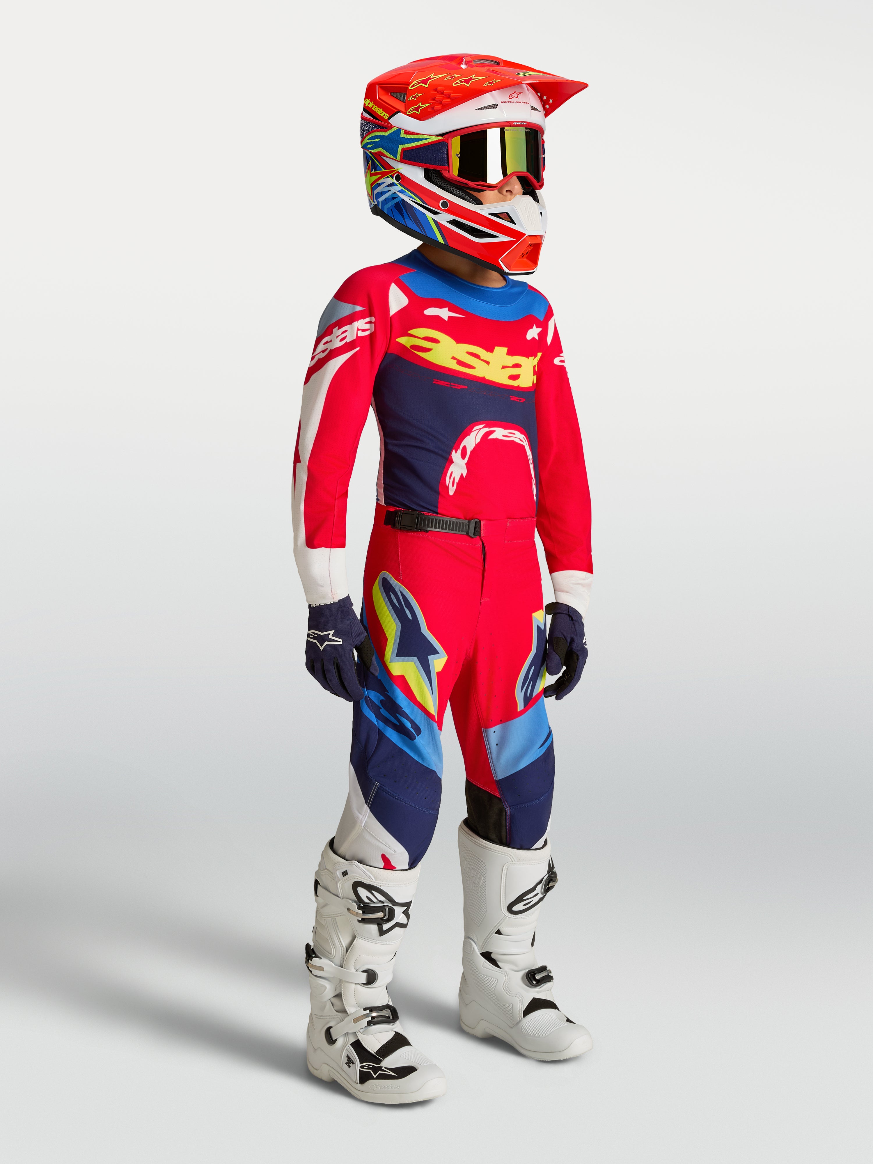 Pantalon Alpinestars Supertech Dyna Junior, motocross, rouge et bleu marine, avec maillot et casque assortis.