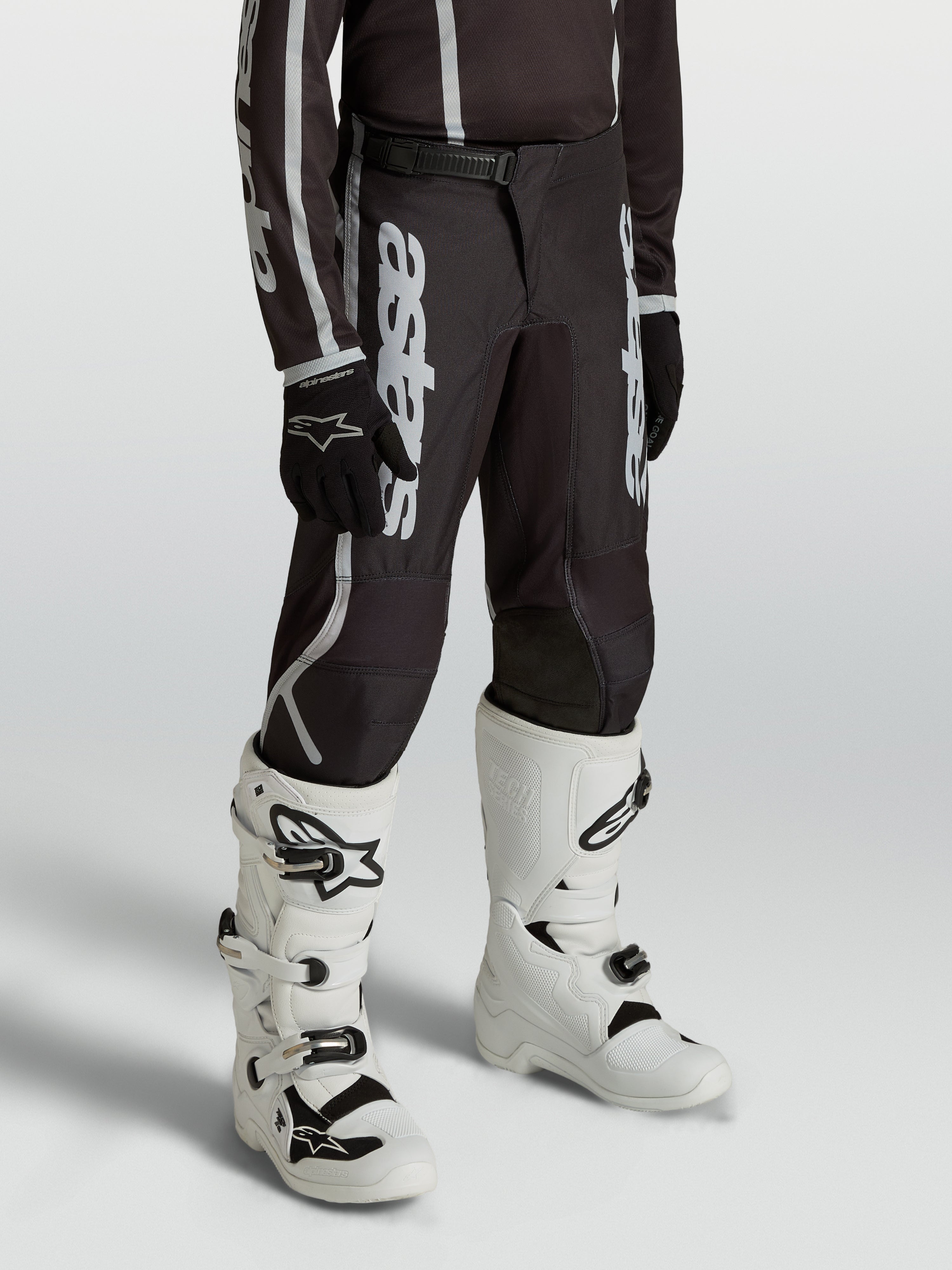 Pantalon Alpinestars Fluid Apex V2 Junior, motocross noir et argenté, coupe ergonomique pré-courbée pour jeunes pilotes.