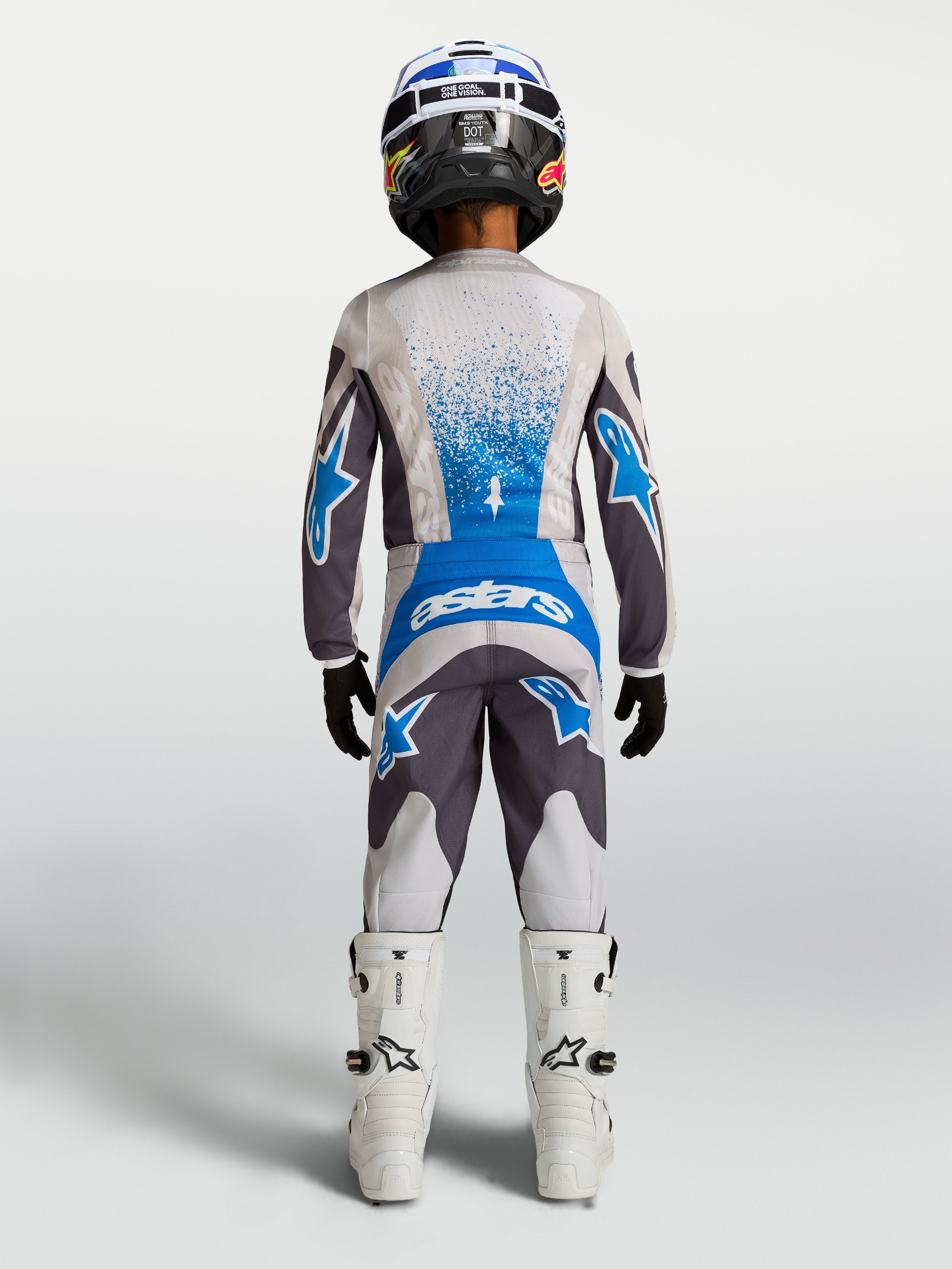 Alpinestars pantalon Fluid Drag Junior, équipement de motocross pour enfant, gris et bleu, vu de dos avec maillot et bottes assortis, conçu pour la performance tout-terrain