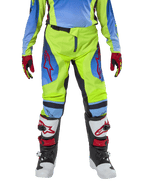 Pantalon Alpinestars Racer Hoen Junior 2024, pantalon de motocross, jaune fluo et bleu Night Navy, avec logos étoiles rouges sur les cuisses, porté avec un maillot assorti, des gants rouges et noirs et des bottes de motocross blanches, noires et rouges, équipement durable pour le tout-terrain