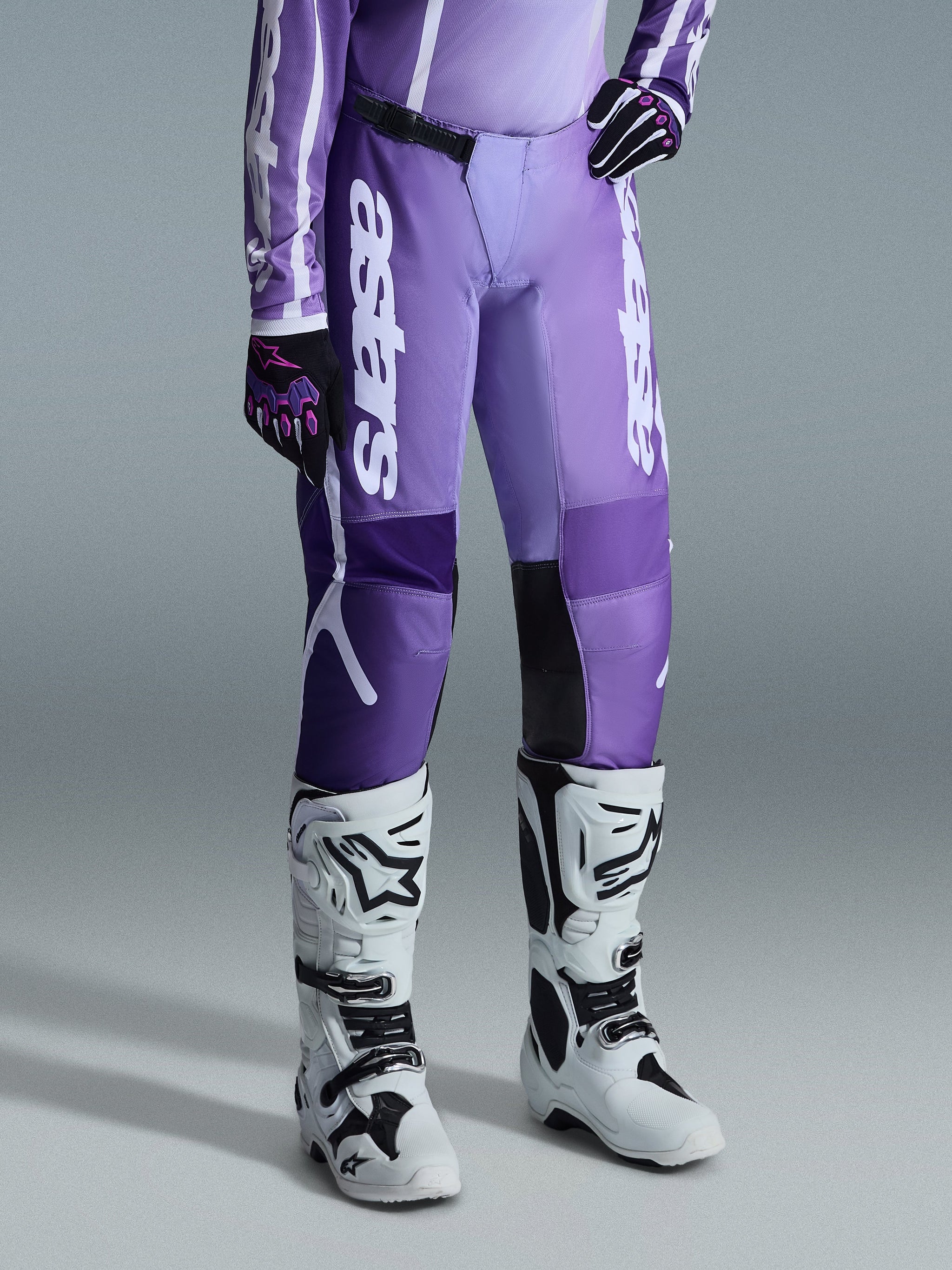 Alpinestars 2026 Woman Stella Fluid Apex Pants, Women's Motocross Pants, Violet and White, featuring vertical white Alpinestars branding on the legs, worn with matching purple jersey and white motocross boots, sporty design for off-road racing