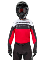 Maillot Alpinestars Pro-Dura, maillot de motocross, noir, rouge vif et blanc, porté avec casque noir et masque, design sportif avec logo Alpinestars audacieux et perforations laser, équipement de course haute performance pour l'enduro et le tout-terrain
