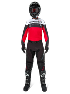 Pilote de motocross portant le maillot Alpinestars Pro-Dura en noir, rouge vif et blanc, avec un pantalon noir, des bottes noires et un casque noir, équipement complet de course tout-terrain