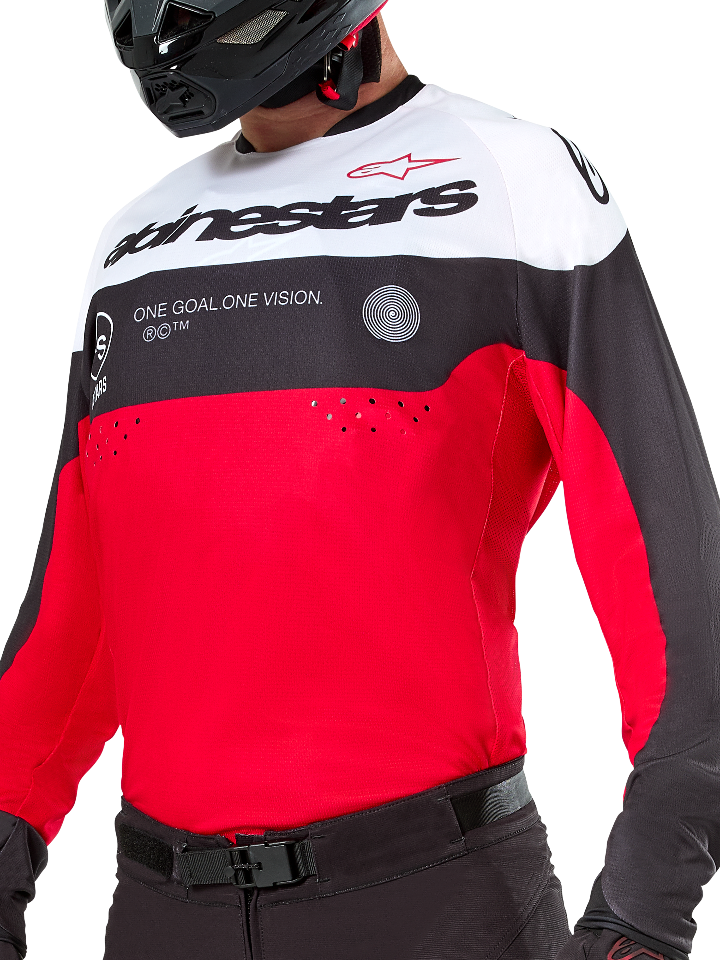 Maillot Alpinestars Pro-Dura, maillot de motocross et d'enduro, noir, rouge vif et blanc, avec le graphisme « ONE GOAL. ONE VISION. » et des perforations laser sur la poitrine, porté avec un pantalon de motocross et un casque noirs.