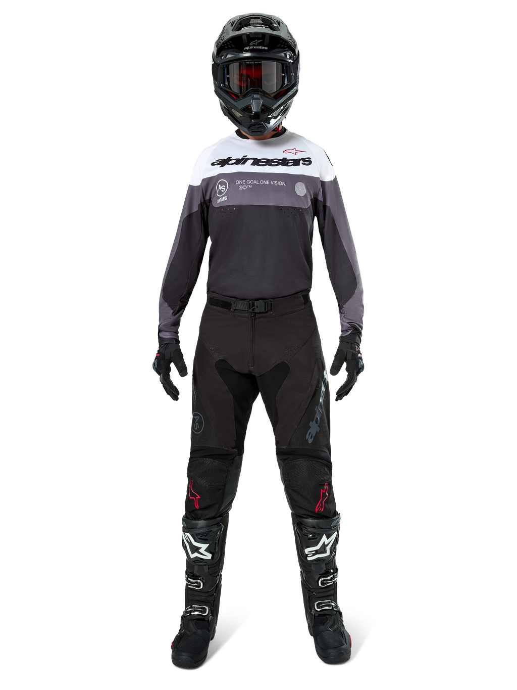 Pilote de motocross portant une tenue de course complète, maillot Pro-Dura en Black Magnet White avec haut de la poitrine blanc et détails gris, associé à un pantalon noir, un casque noir avec lunettes sombres, des bottes noires et blanches, et des gants noirs, ensemble coordonné pour l'enduro et le tout-terrain