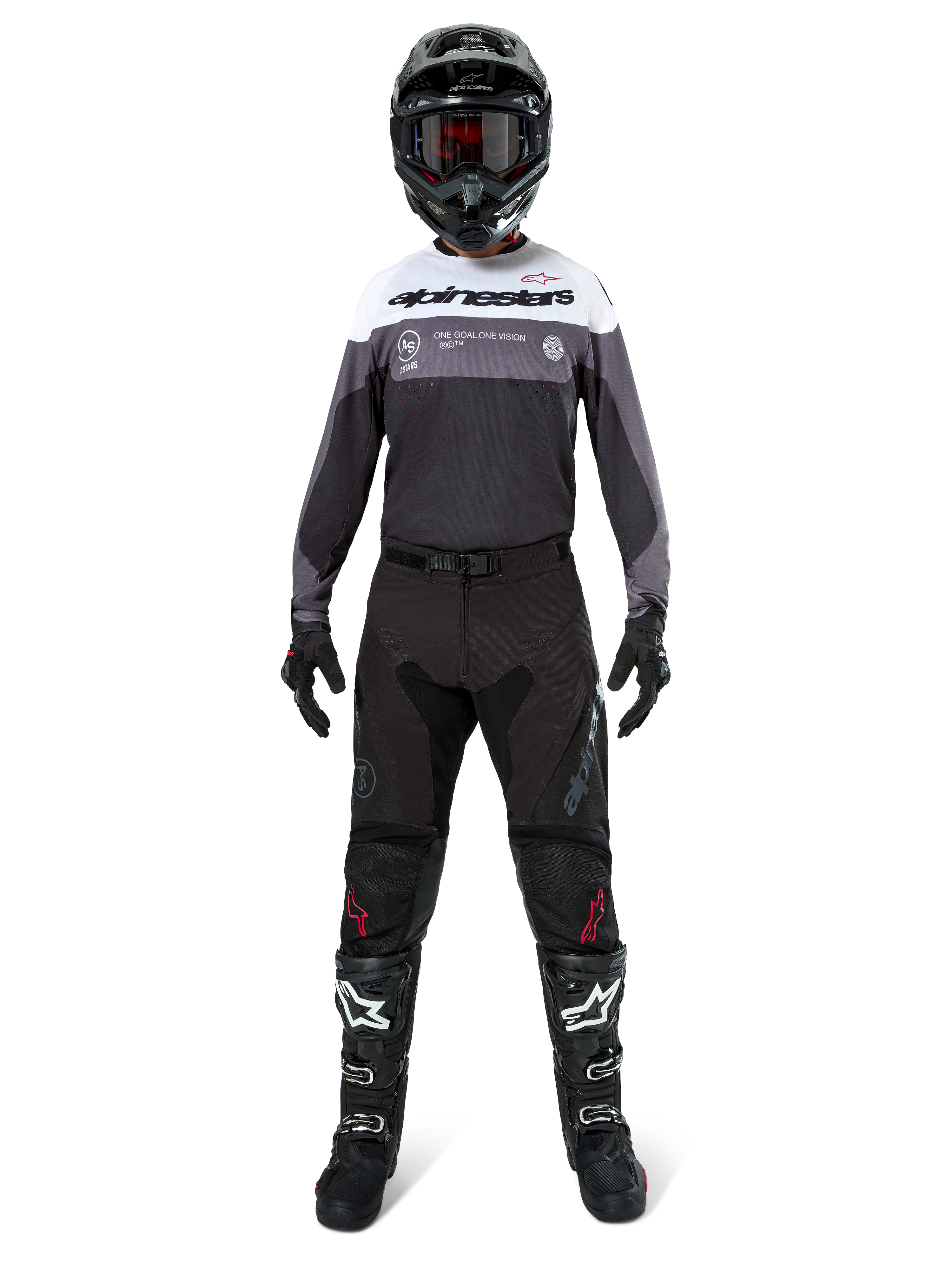 Pilote de motocross portant une tenue de course complète, maillot Pro-Dura en Black Magnet White avec haut de la poitrine blanc et détails gris, associé à un pantalon noir, un casque noir avec lunettes sombres, des bottes noires et blanches, et des gants noirs, ensemble coordonné pour l'enduro et le tout-terrain