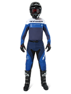 Motocross rider wearing complete racing gear, Pro-Dura Jersey in Navy, Bright Blue and White, matching blue and navy pants, black helmet with red goggles, black and white boots, coordinated outfit for enduro and off-road riding