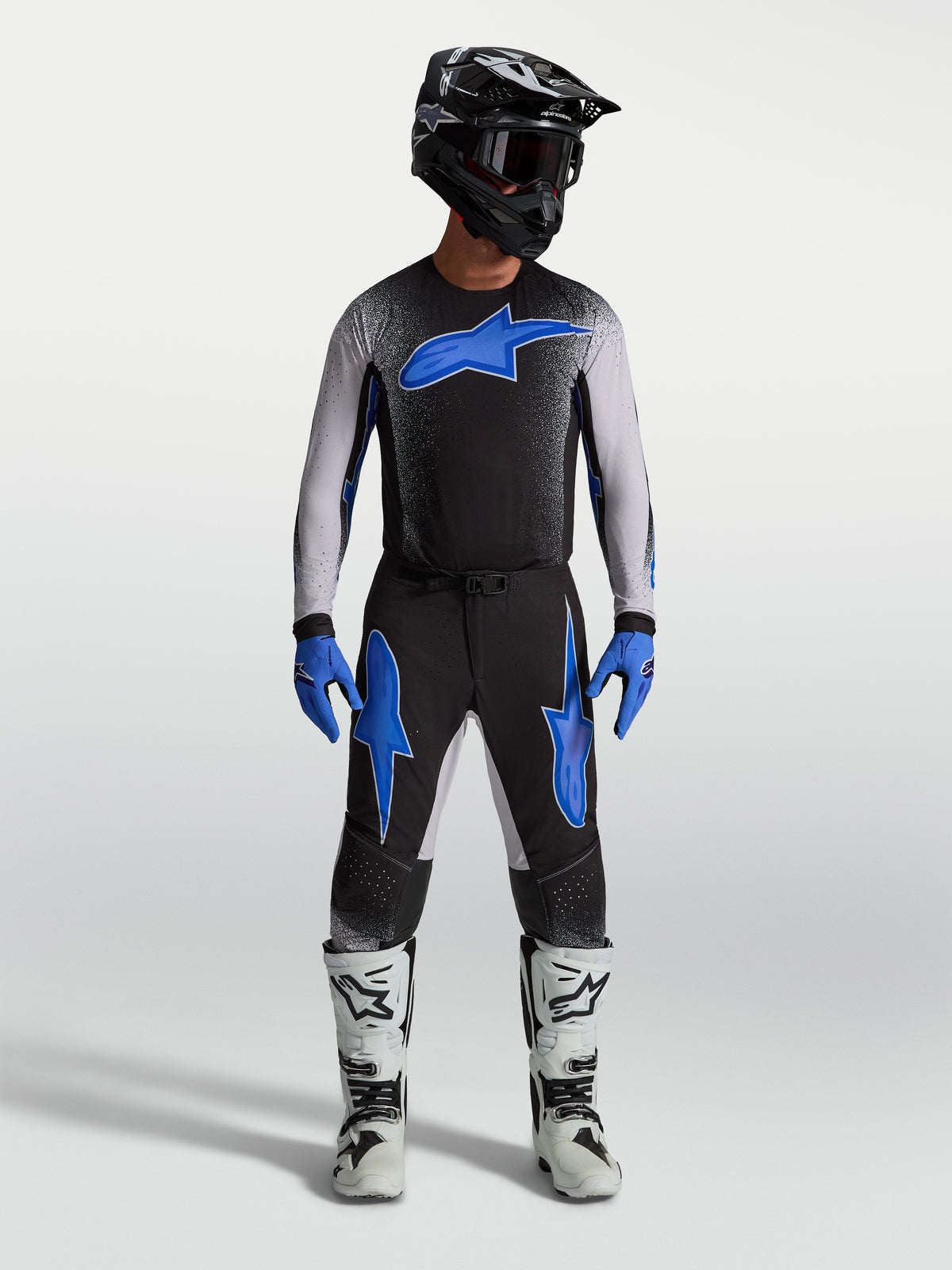 Maillot Supertech Hiten AFD et ensemble de motocross Alpinestars, noir et bleu, pour homme, coupe racing ergonomique, équipement tout-terrain porté avec bottes et casque.