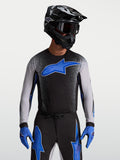 Maillot Supertech Hiten AFD Alpinestars, maillot de motocross pour homme, noir et bleu, technologie de protection AFD, coupe racing athlétique, porté par un mannequin avec casque et gants de moto